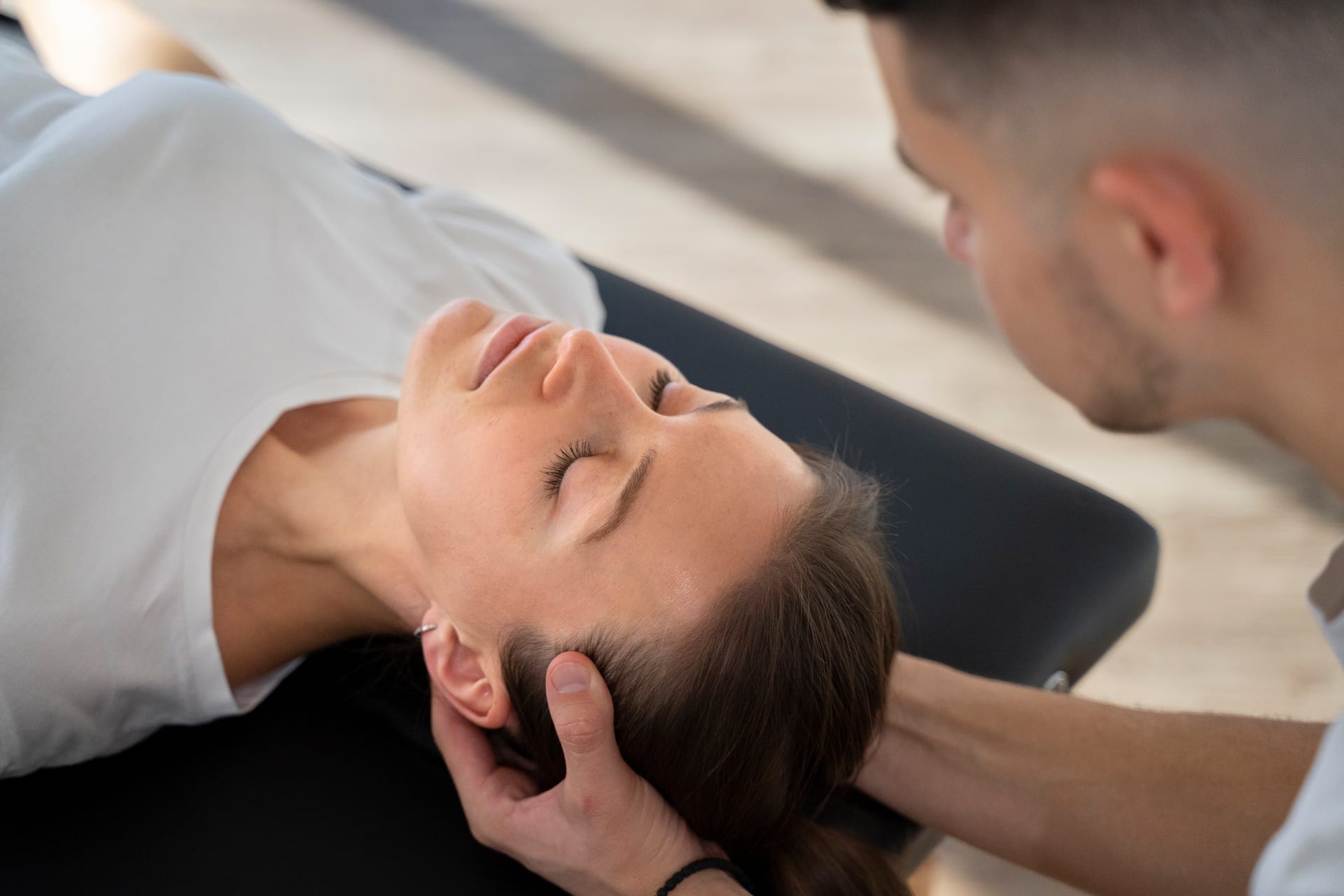 Physical therapist performing gentle manual therapy at the base of a patient's skull