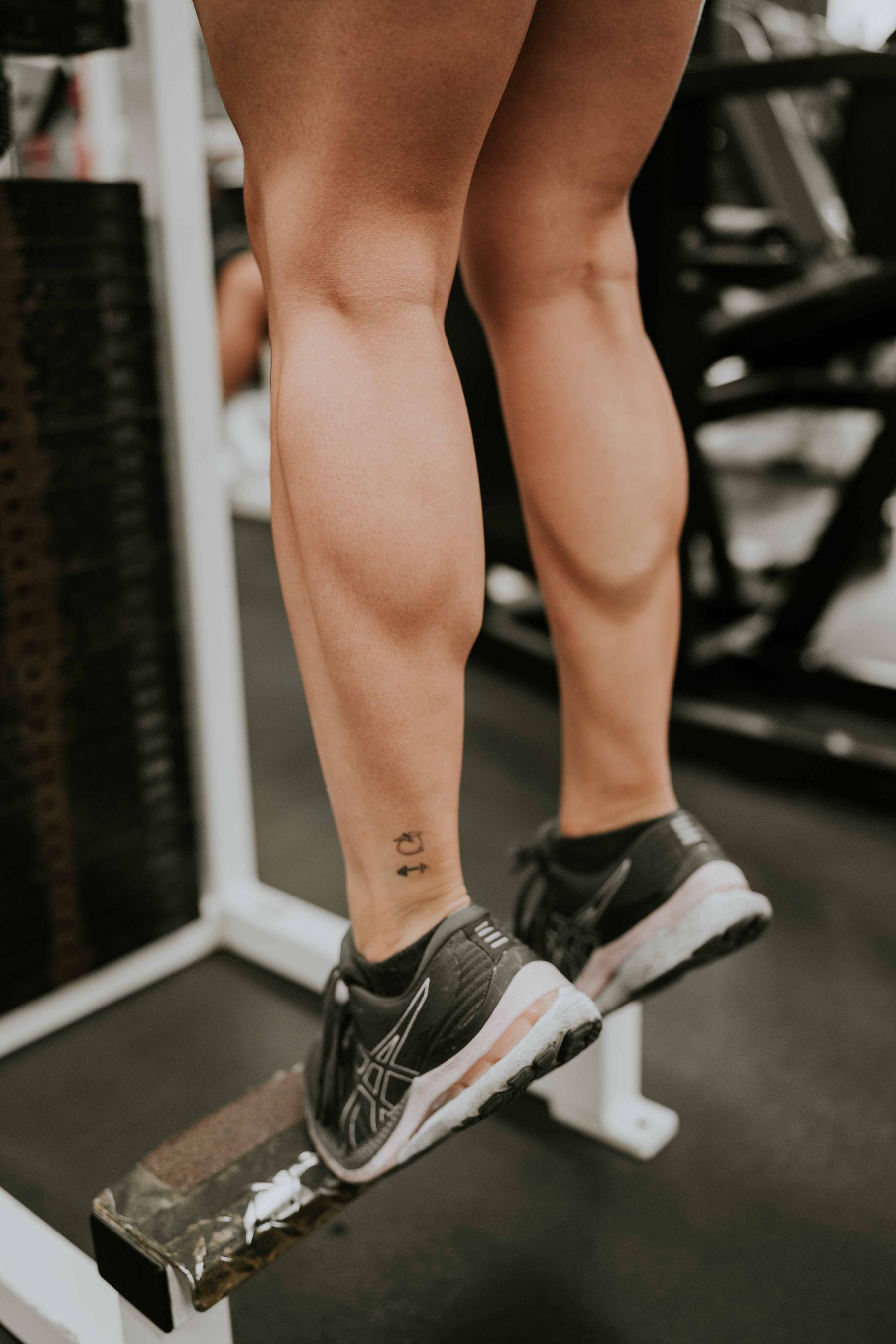 Woman performing a loaded calf raise exercise in the gym