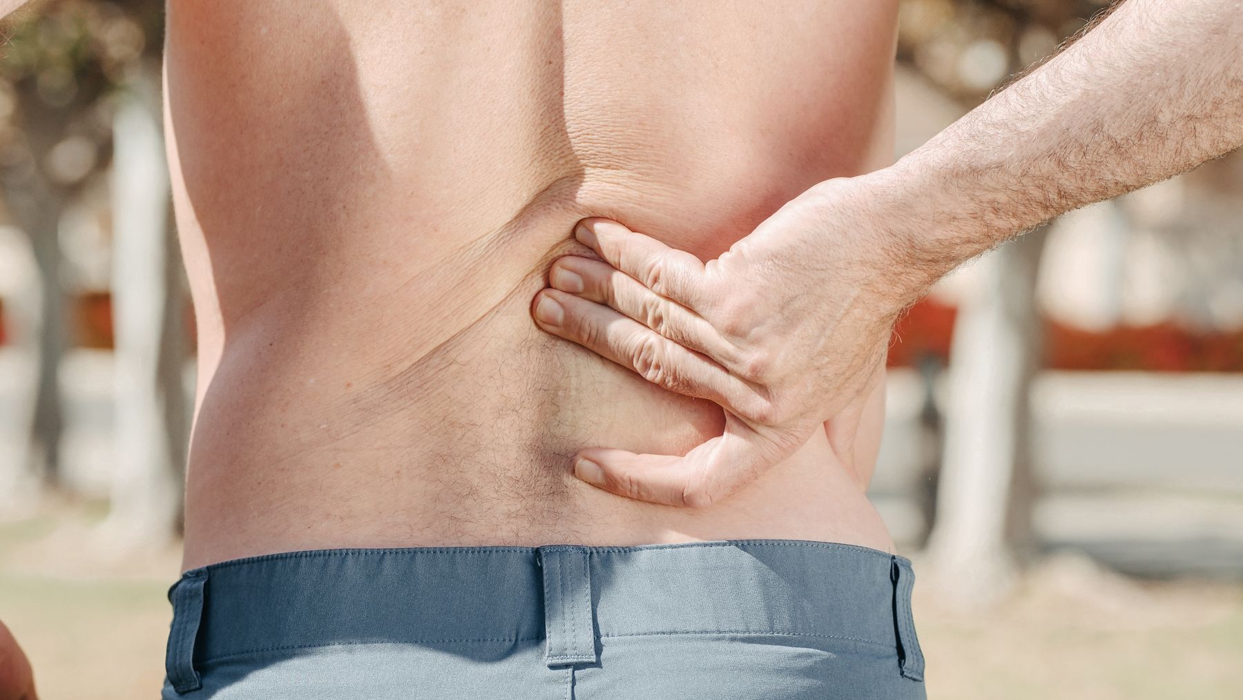 Man pressing his hands into his painful lower back