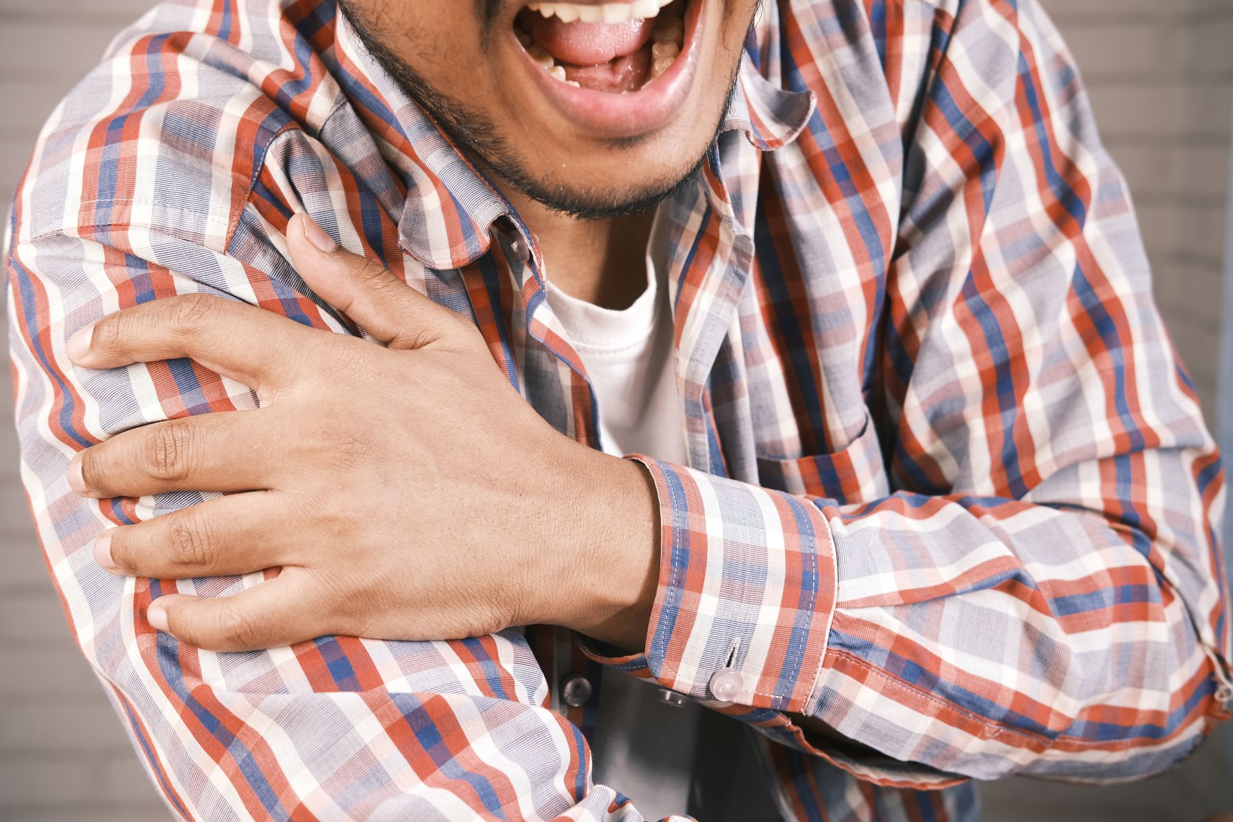 Man wincing and gripping his painful shoulder