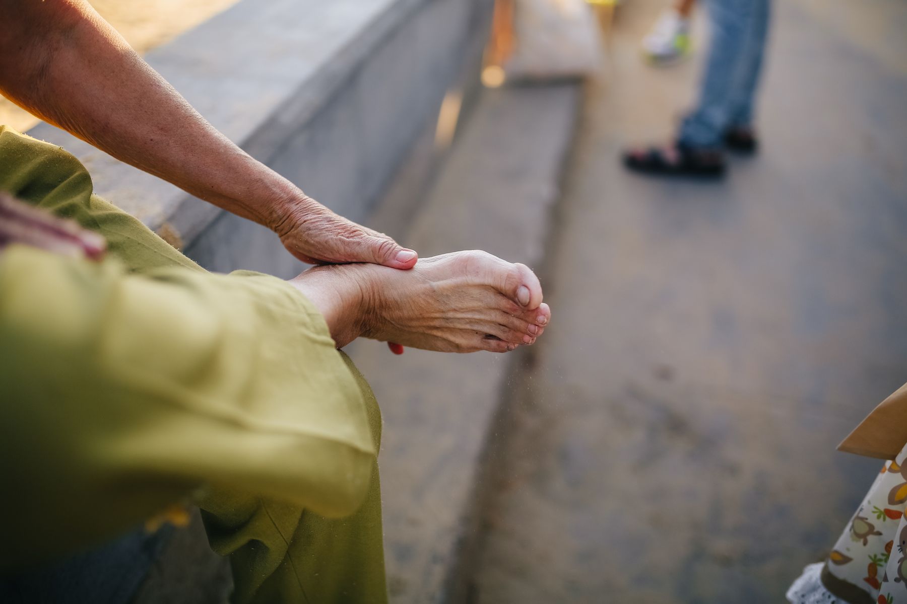 Older adult massaging the sole of their bare foot
