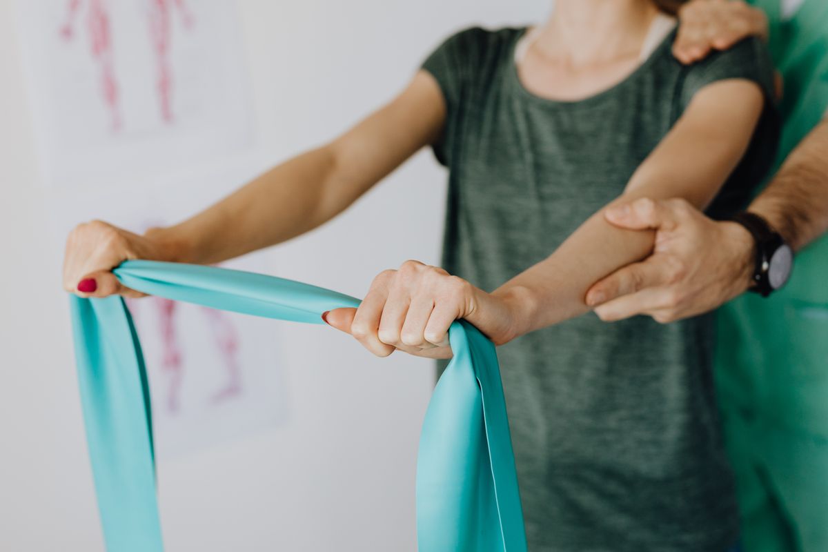Clinician guiding shoulder strengthening with a resistance band