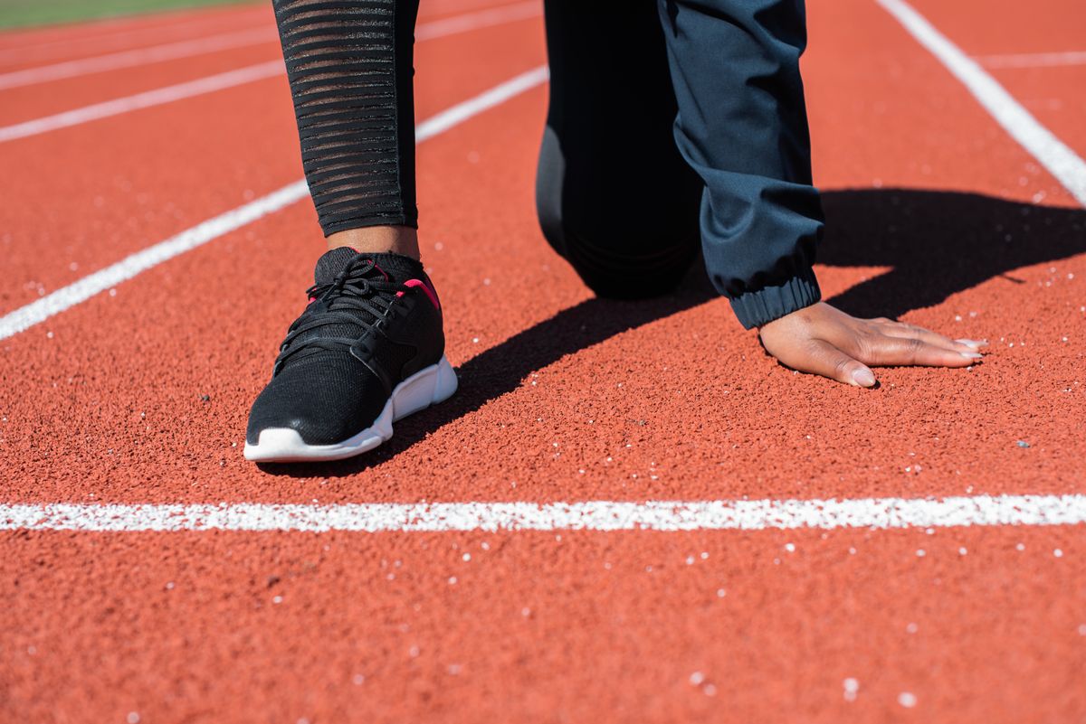 Athlete in a sprint start position on a track during return-to-sport training