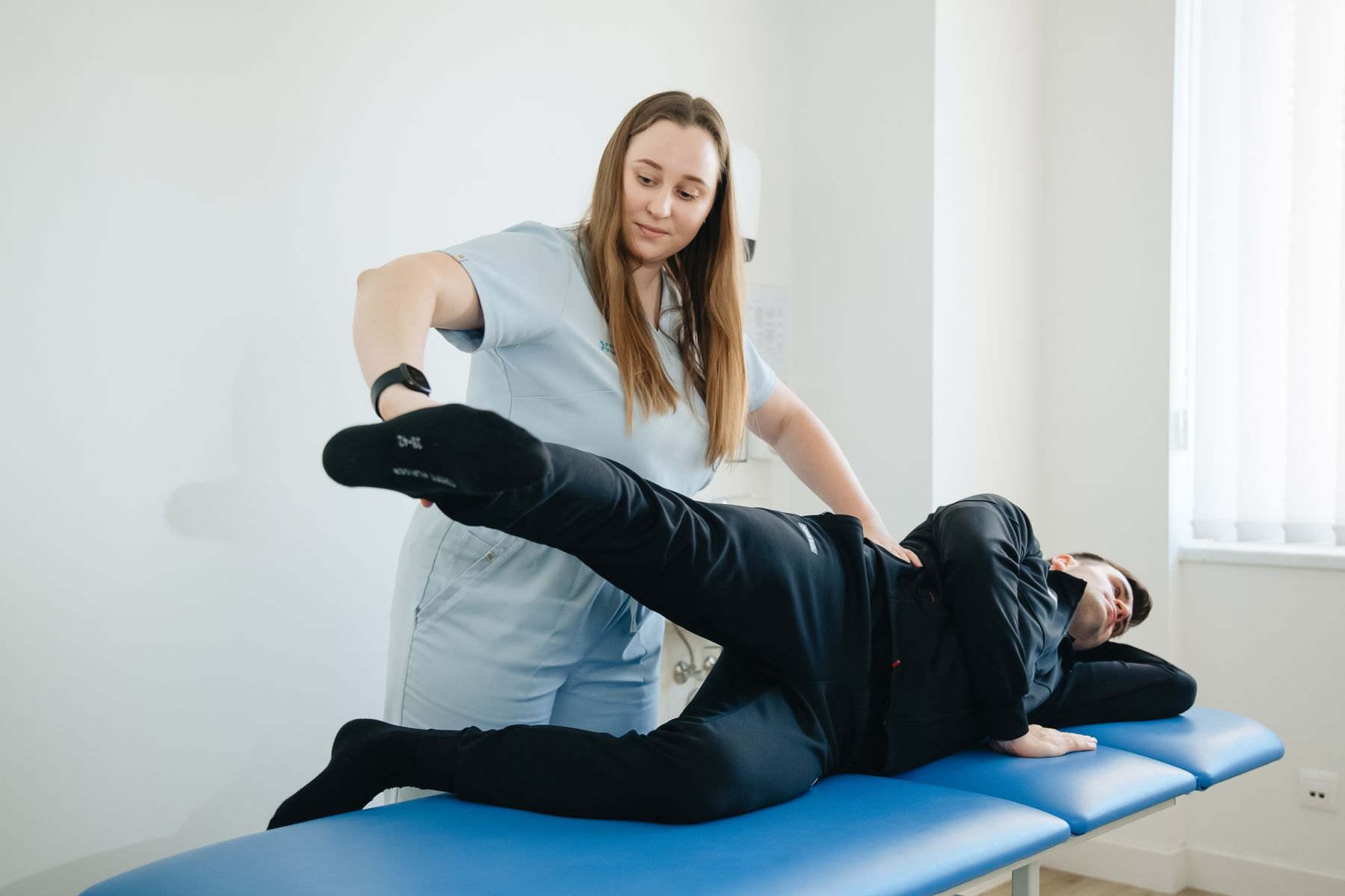 Physical therapist performing a straight leg raise nerve tension test on a patient with suspected lumbar disc herniation