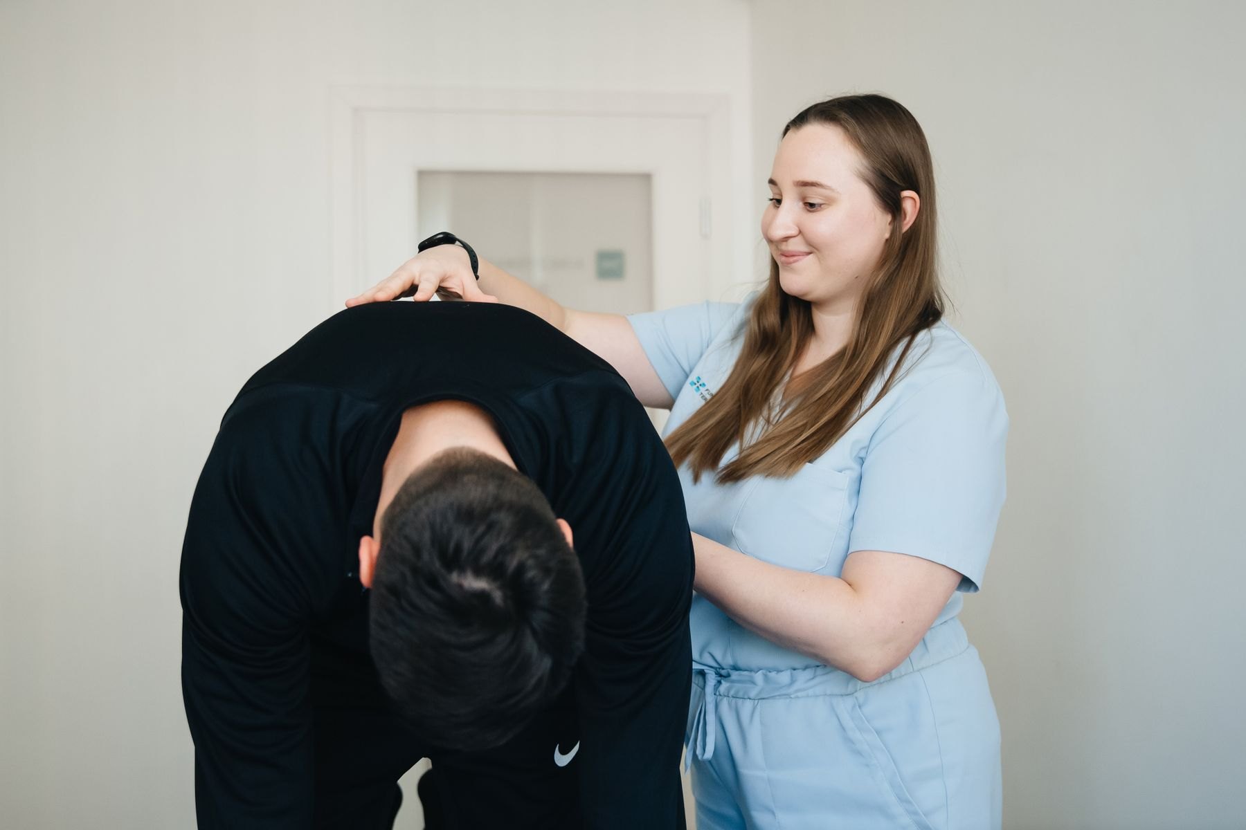 Physical therapist assessing lumbar forward bending in a patient with a herniated disc