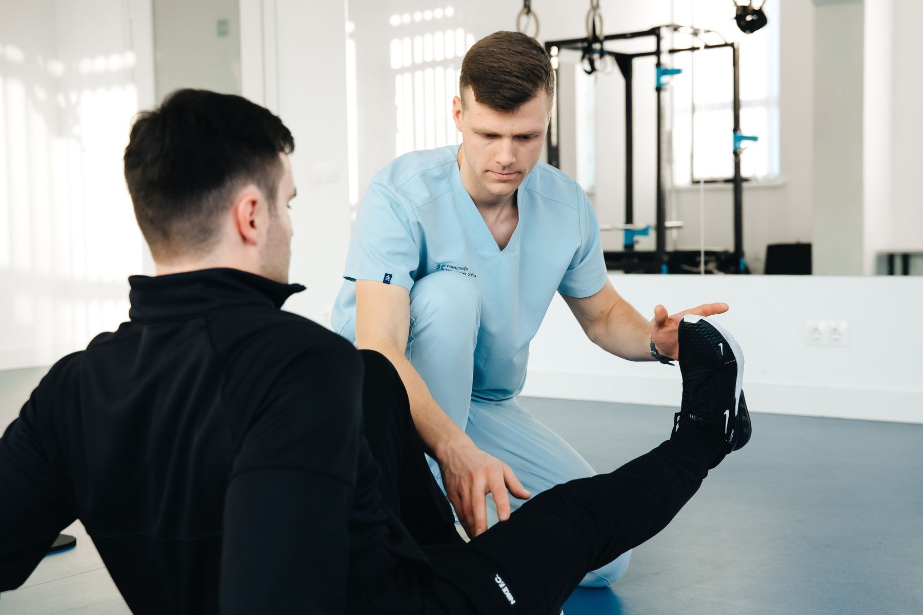 Physical therapist coaching a seated leg extension exercise during knee replacement rehabilitation