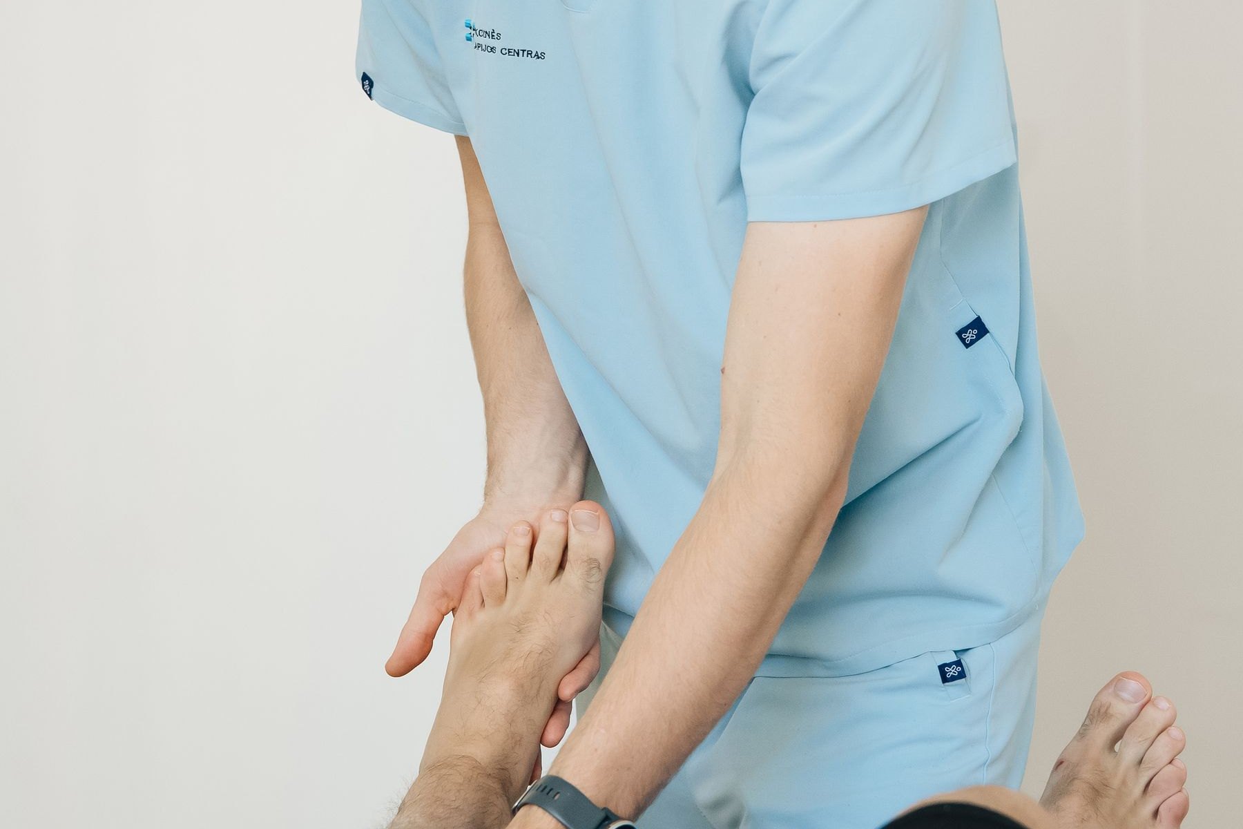 Physical therapist palpating a patient's foot to locate focal bone tenderness