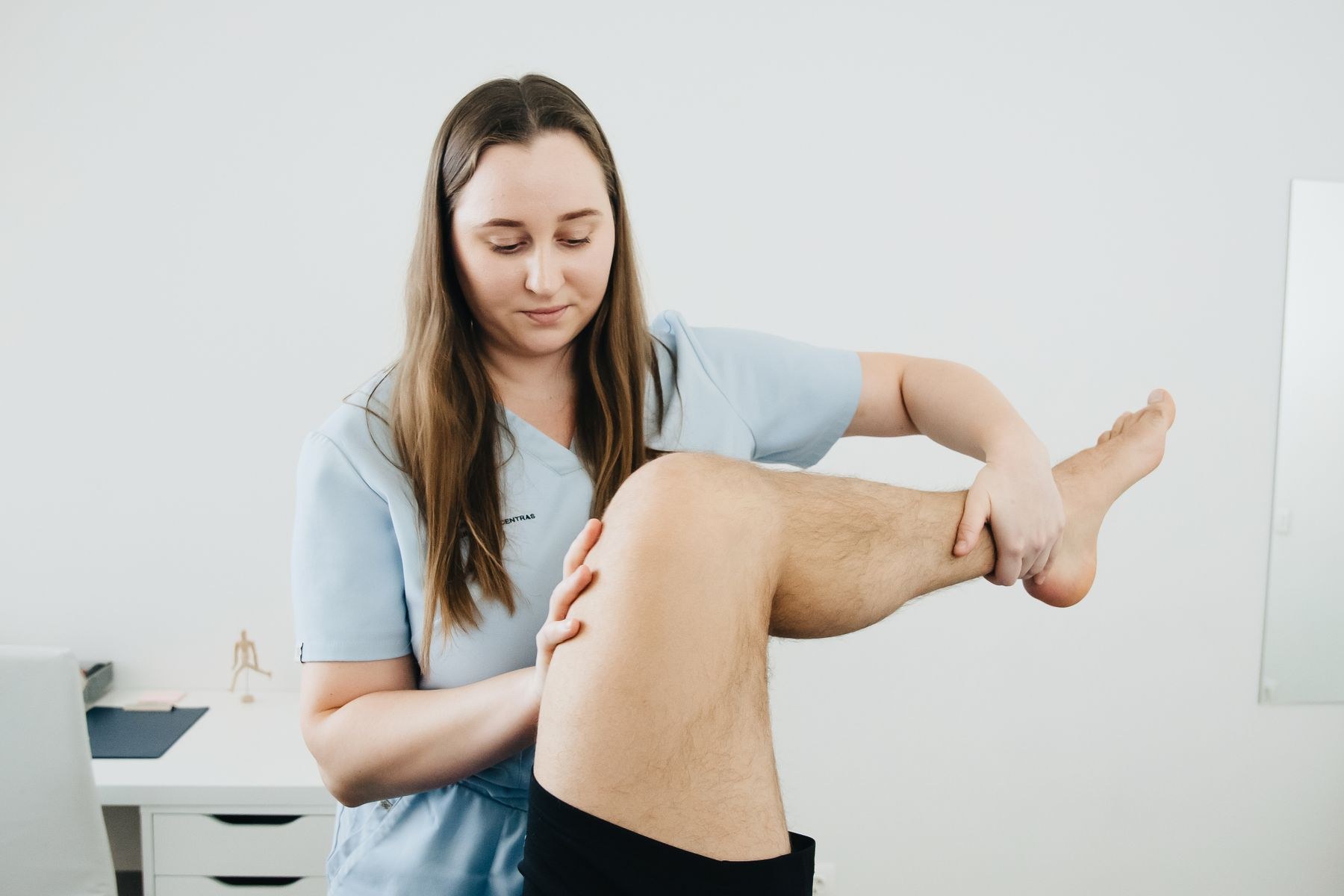 Physical therapist guiding a patient's knee into flexion during rehabilitation after total knee replacement