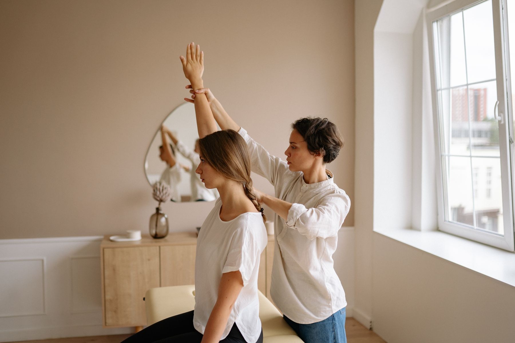 Physical therapist guiding a patient through assisted shoulder elevation during post-surgical rehabilitation