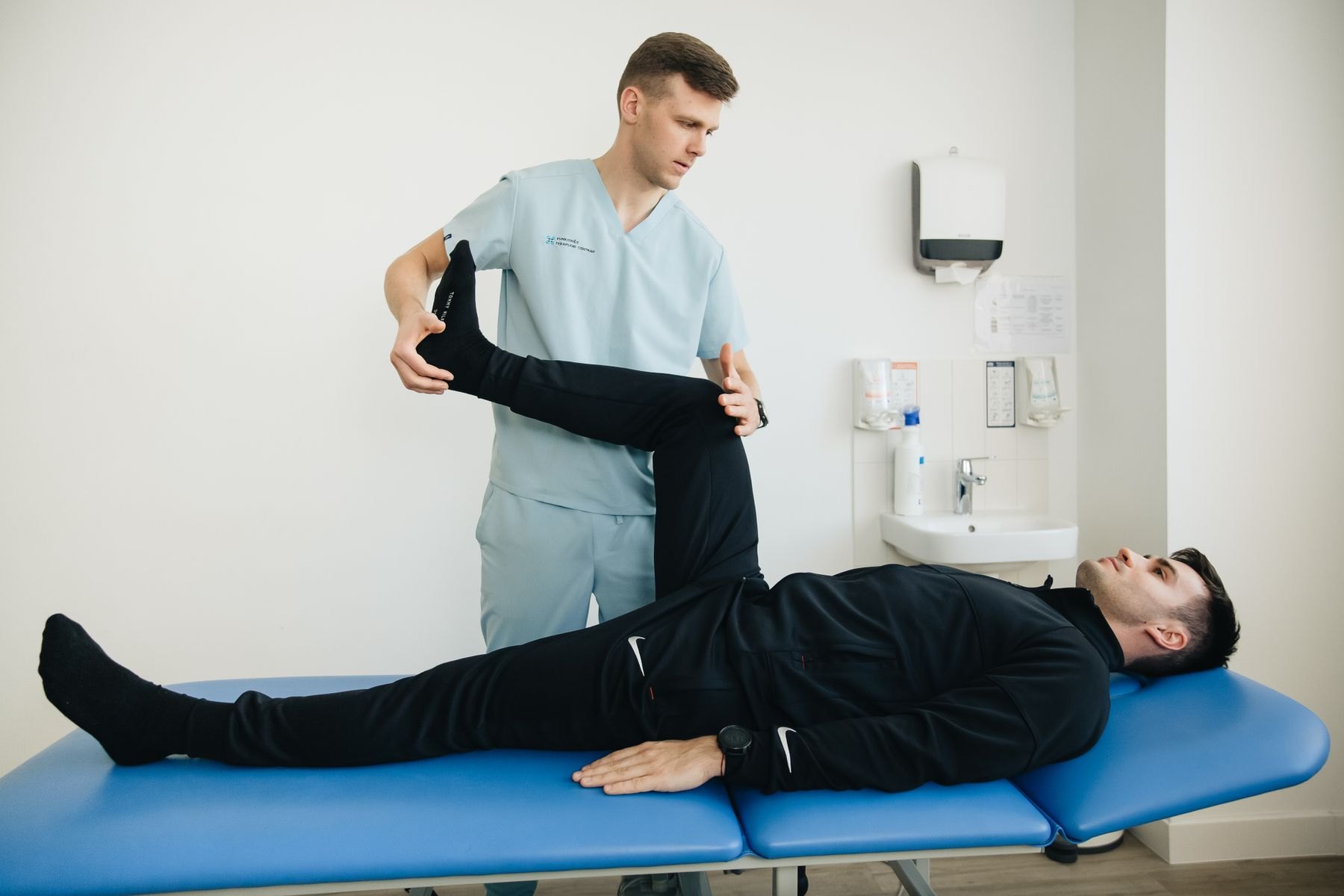 Physical therapist performing a straight leg raise to assess hamstring length and pain