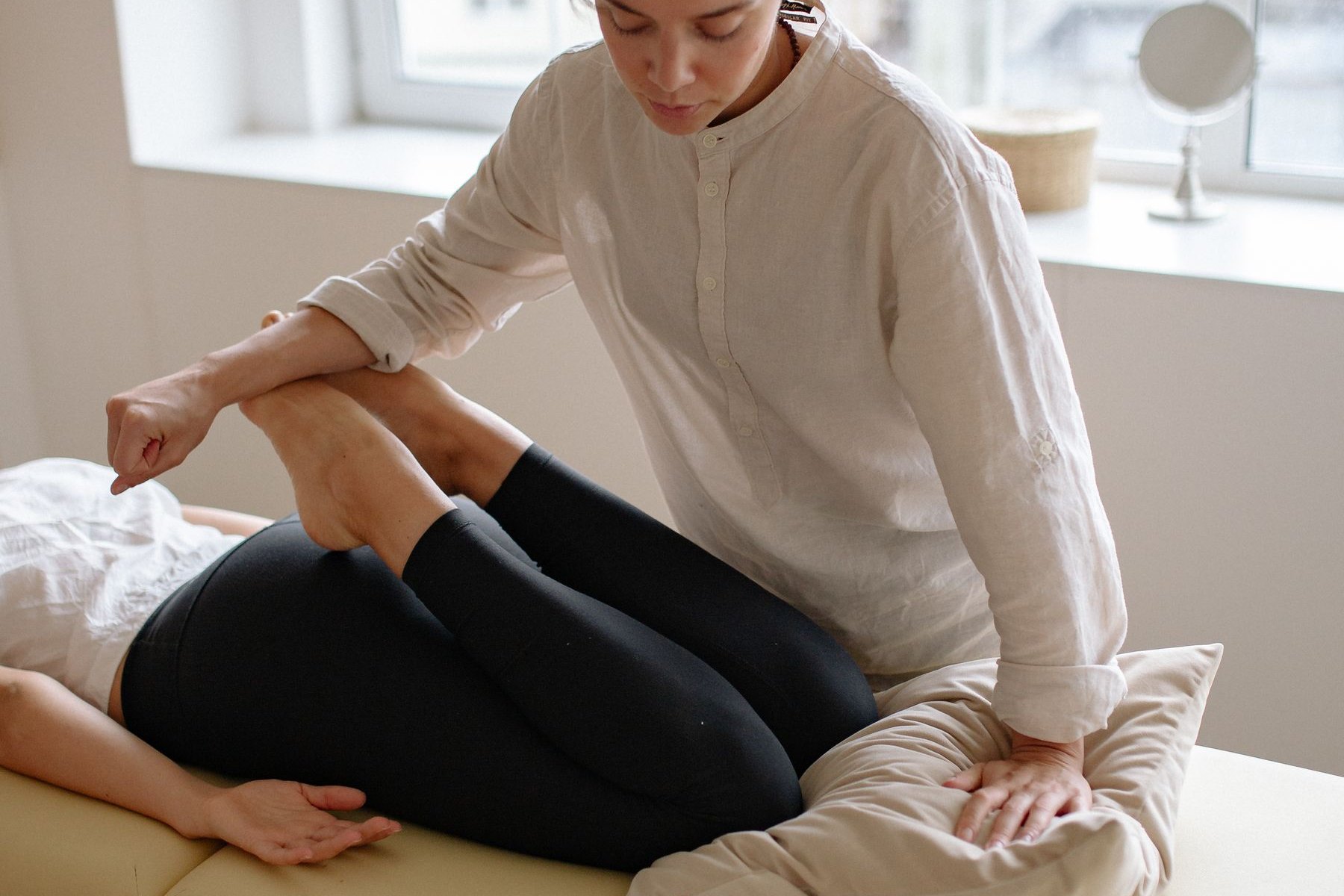 Physical therapist supporting a patient's bent knee during a meniscus tear assessment