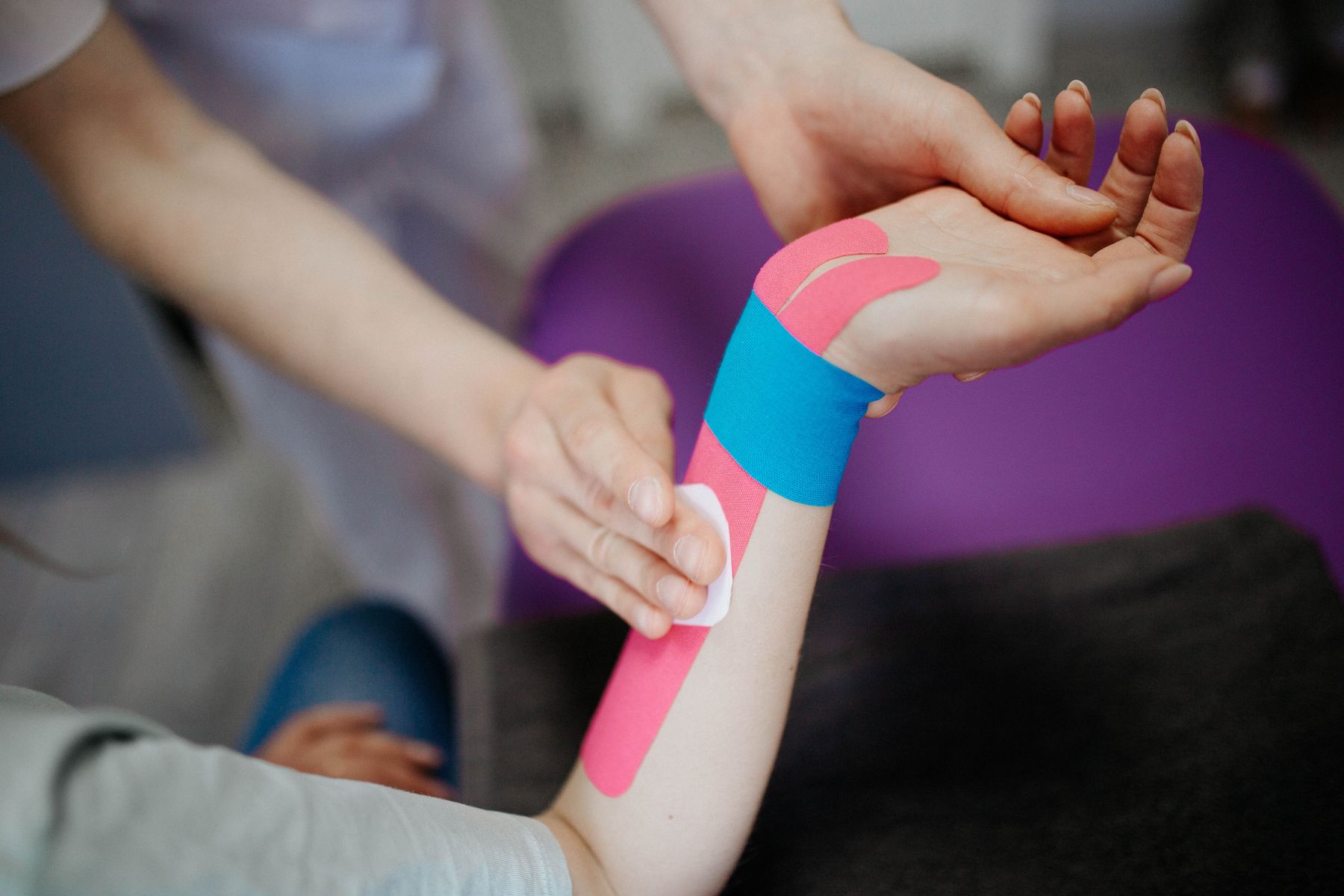 Therapist applying supportive tape to a patient's forearm and wrist