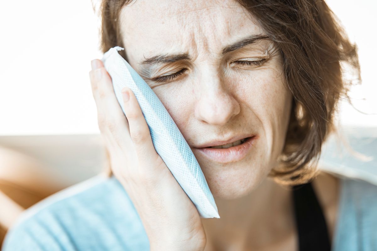 Woman holding her jaw in pain from TMJ dysfunction