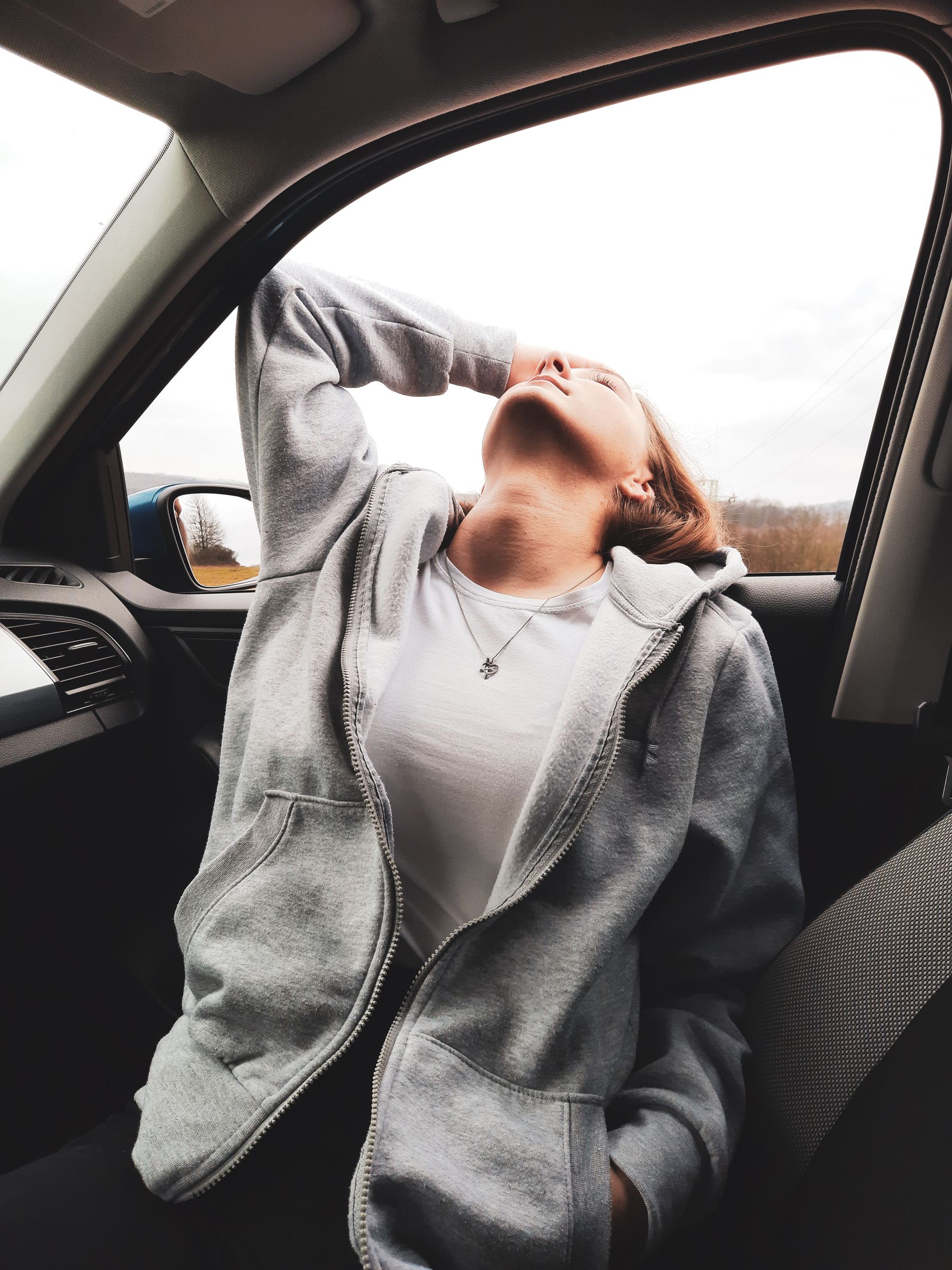 Woman in a car seat holding her neck in discomfort
