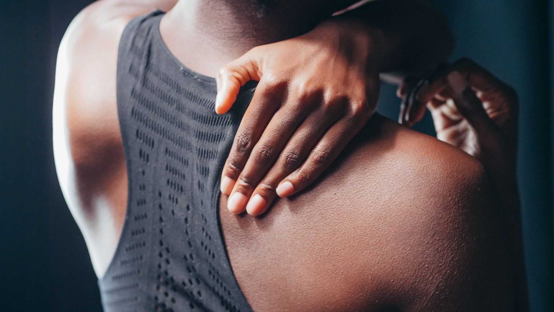 Woman reaching over her shoulder toward stiff, painful tissue