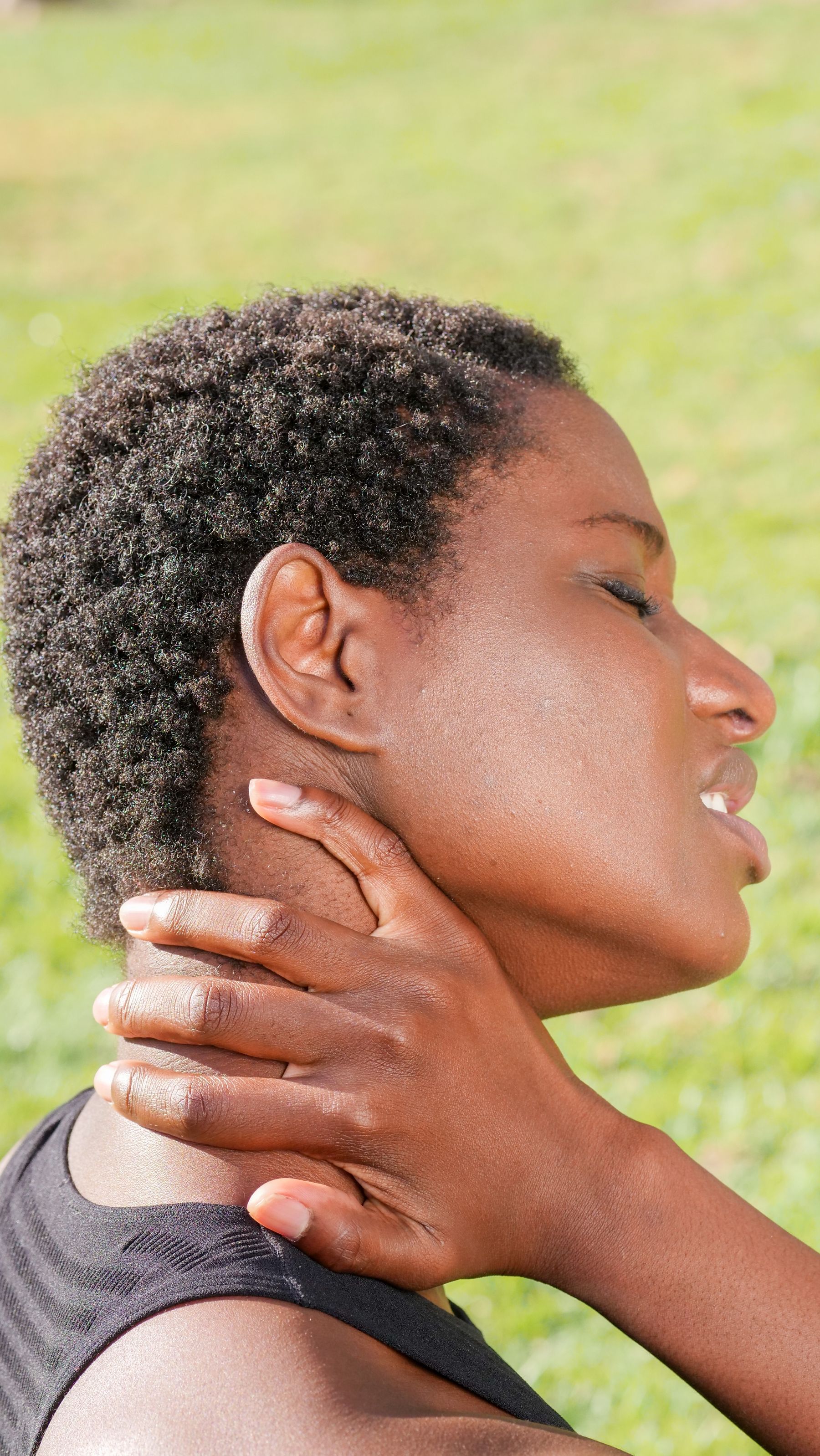 Woman outdoors holding the back of her neck in pain