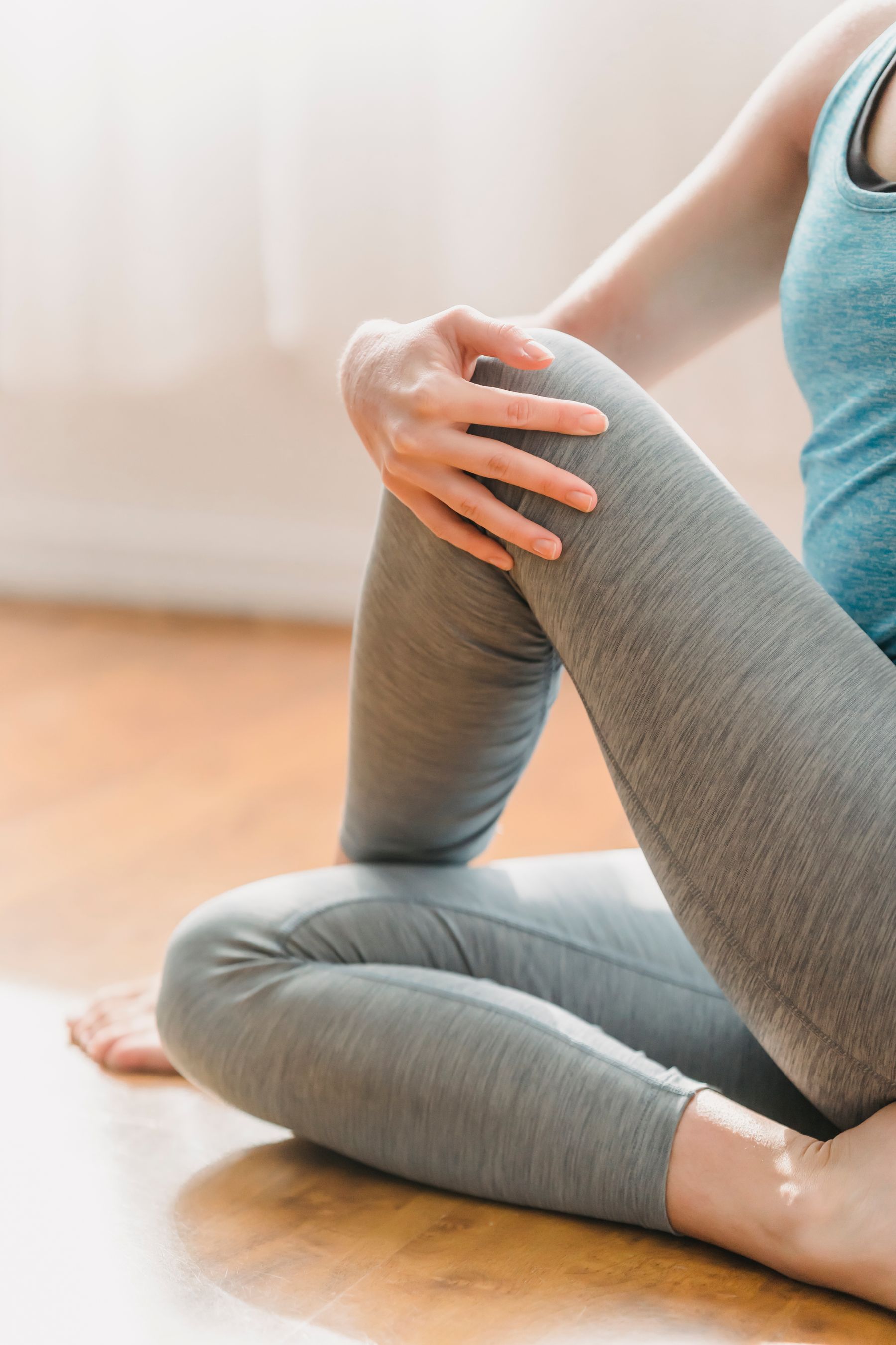 Woman performing a seated hip and leg stretch on the floor at home
